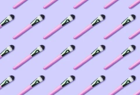 Pattern made from make up brushes on violet background. Stock Photos
