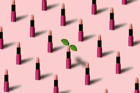 Pattern made with many red lipsticks on pink pastel backdrop. One lipstick wi 스톡 사진