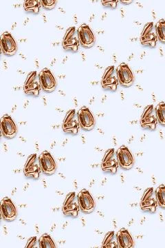 Pattern made of number 40 golden air balloons with ribbons confetti. Stock Photos
