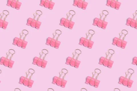 Pattern made of pink paper clips on a purple pastel background. Stock Photos