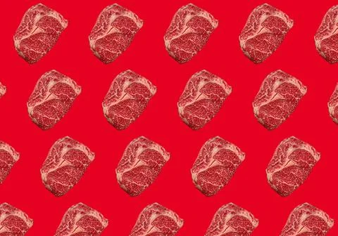 Pattern made of raw meat beef marbled prime cut steak Ribeye on red clean Stock Photos