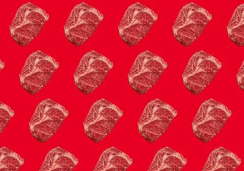 Pattern made of raw meat beef marbled prime cut steak Ribeye on red clean Stock Photos