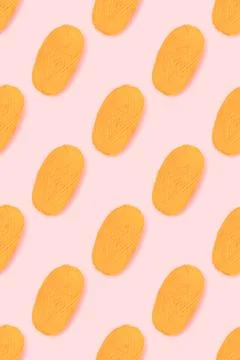 Pattern made of skein of yellow wool thread on a pink background. Stock Photos