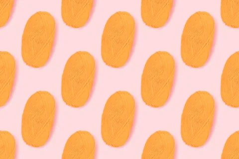 Pattern made of skein of yellow wool thread on a pink pastel background. Foto stock