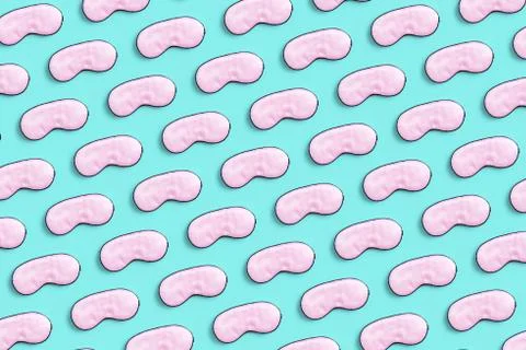 Pattern made with sleeping mask. Pink silk sleep mask for eyes on a blue back Stock Photos