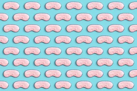 Pattern made with sleeping mask. Pink silk sleep mask for eyes on a blue back Stock Photos