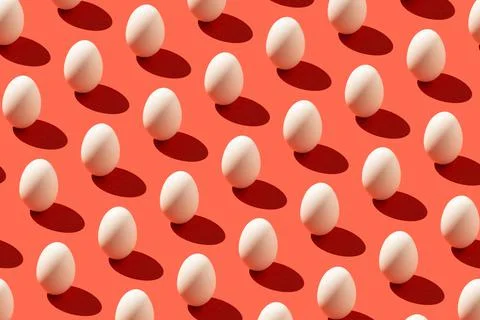 Pattern made of white eggs and sharp shadow on pastel red background. Minimal Stock Photos
