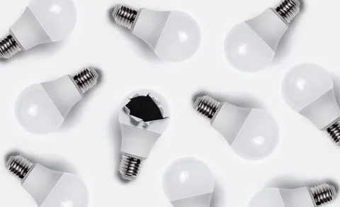 Pattern of many light bulbs; one bulb with torn hole on white background. Stock Photos