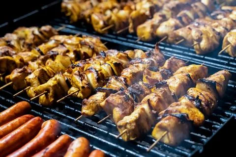 Pattern meat skewers fried with a crust on a wooden skewer and sausage lies o Stock Photos