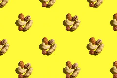Pattern from mix nuts on yellow background. Pattern from different nuts. Tren Stock Photos