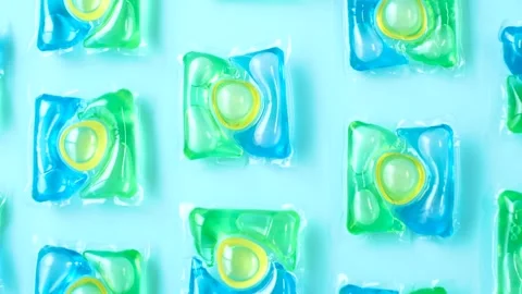 Pattern of multicolored capsules with liquid washing powder on a blue background Stock Footage 312842392