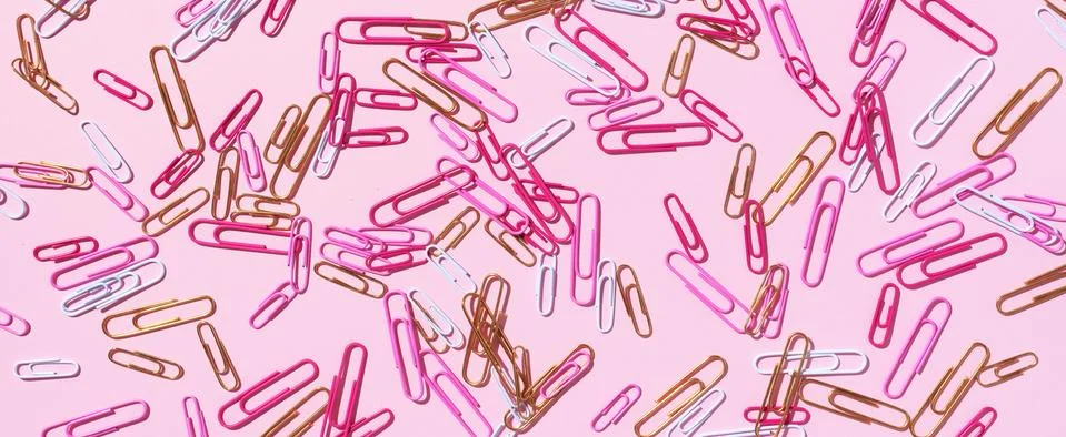 Pattern of multicolored paper clips on pink background. Back to school. Office Stock Photos