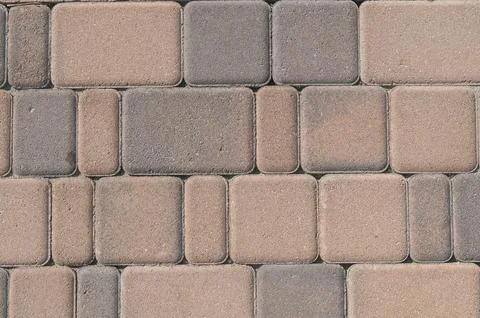 Pattern of multicolored tan and grey stone paving blocks Stock Photos