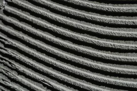 Pattern of notched trowel strokes on the gray surface of cement putty for laying Foto stock