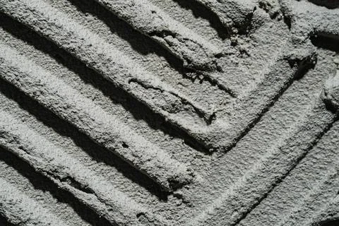 Pattern of notched trowel strokes on the gray surface of cement putty for laying Stock Photos