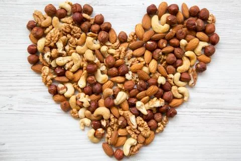 Pattern of nuts in heart form. Cashew, hazelnuts, walnuts, almonds on white Foto stock
