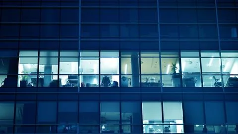 Pattern of office buildings windows illuminated at night. Stock Photos