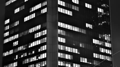 Pattern of office buildings windows illuminated at night. Stock Photos