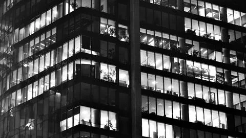 Pattern of office buildings windows illuminated at night. Stock Photos