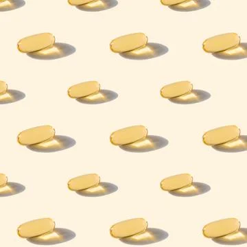 A pattern of omega capsules on a beige background. Stock Photos