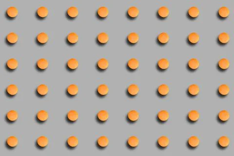 A pattern with orange macarons with a shadow on a gray background. Background Stock Photos