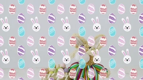 Pattern overlay receding, plush bunny emerging on table with pastel egg basket Stock Footage 330916791