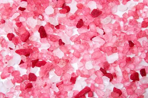 Pattern with pink bath salt grain scattered on the marble surface Stock Photos
