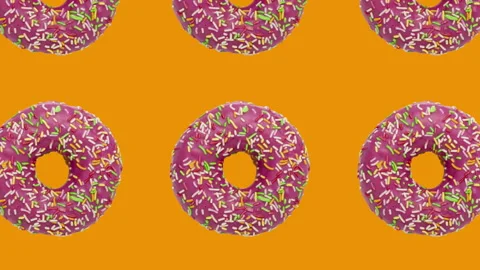 Pattern with pink rotating doughnuts on an orange background Stock Footage 148996401