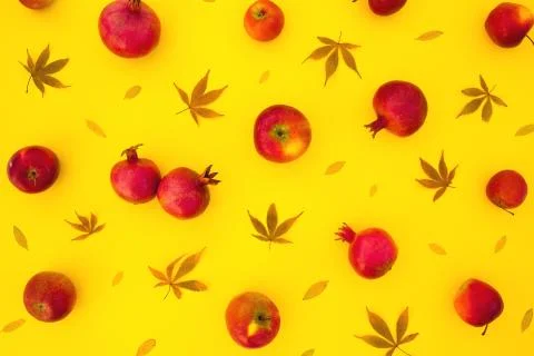 Pattern of pomegranate fuits with fall leaves isolated on bright yellow backg Stock Photos