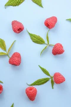 Pattern of raspberry and green leaves on blue background. Flat lay summer ber Stockfoto's