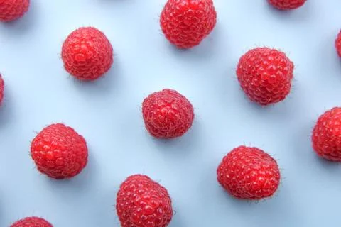 Pattern of raspberry on blue background. Flat lay summer berries - red raspbe Stock Photos