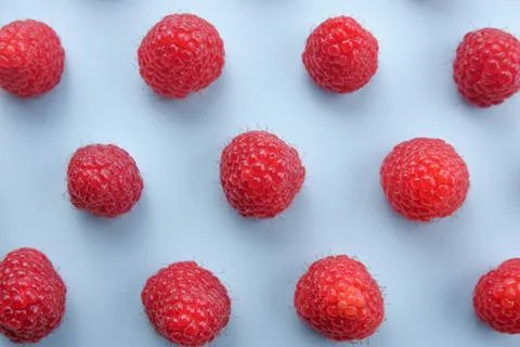 Pattern of raspberry on blue background. Flat lay summer berries - red raspbe Stock Photos