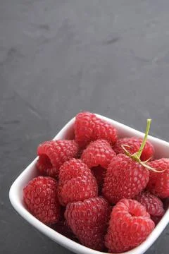Pattern of raspberry on dark rock background. Flat lay summer berries - red r Stock Photos