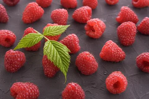 Pattern of raspberry on dark rock background. Flat lay summer berries - red r Stock Photos
