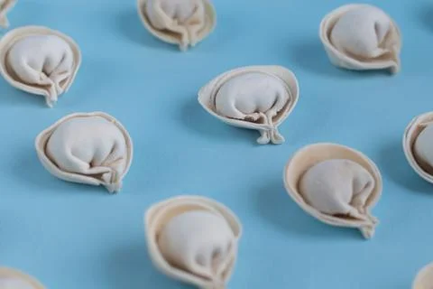 A pattern of raw, frozen dumplings on a light blue background. Фото