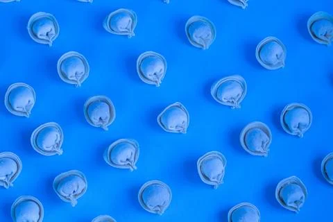 A pattern of raw, frozen dumplings on a light blue background. Foto stock
