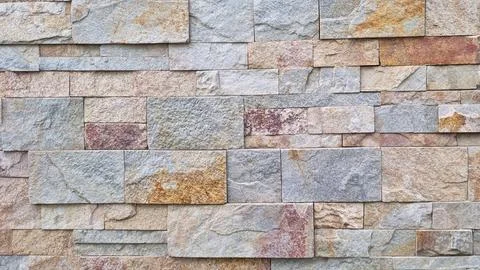Pattern of rectangular natural stone tiles in mixed earthy tones forming Foto stock