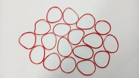 Pattern of Red Rubber Bands Scattered on White Background Foto stock