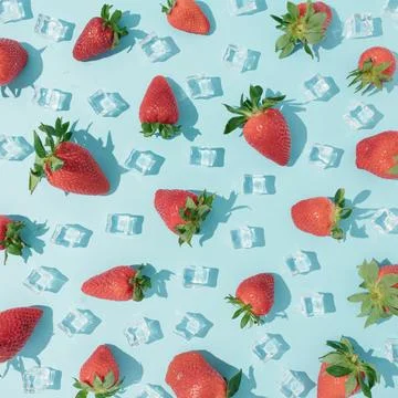 Pattern of red strawberries with ice cubes on the bright blue background Foto stock