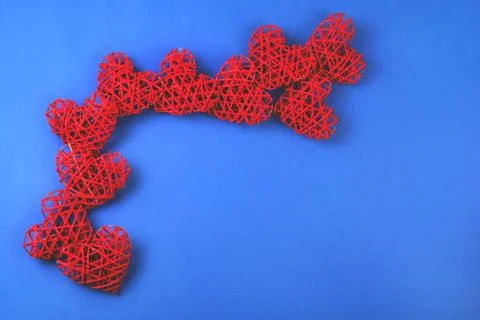 Pattern of the red wicker hearts on the cornflowerblue background. Stock Photos