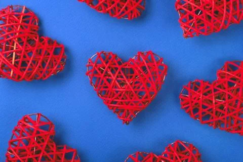 Pattern of the red wicker hearts on the cornflowerblue background. Stock Photos