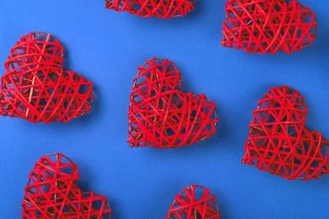 Pattern of the red wicker hearts on the cornflowerblue background. Stock Photos
