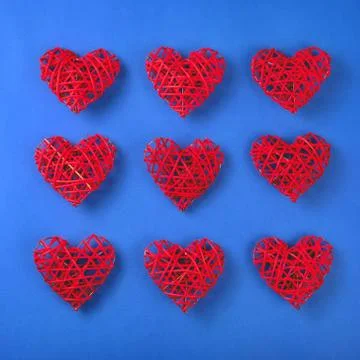 Pattern of the red wicker hearts on the cornflowerblue background. Stock Photos