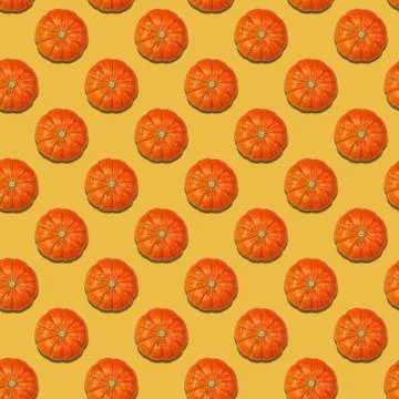 Pattern with repeated pumpkins on a bright yellow background. Top view. Stock Photos