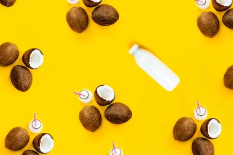 Pattern with ripe coconuts and bottle with drink on yellow background. Top View Stock Photos