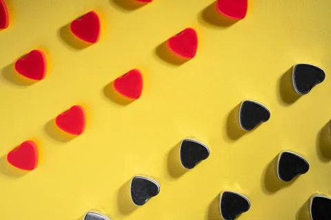 Pattern of rows of red and dark gray hearts on isolated yellow studio background Stock Photos