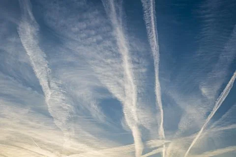 Pattern of several aircraft contrails in the sunset sky Stock Photos