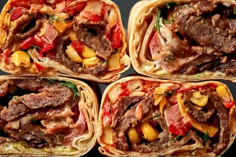 Pattern of shawarma cuts with meat and vegetables on a dark background. Close Stock Photos