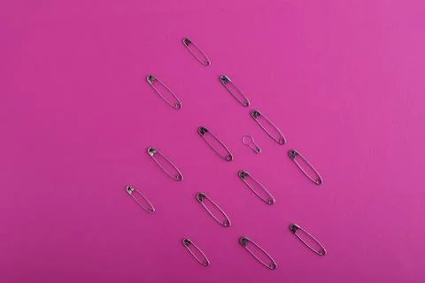 A pattern of silver safety pins of different sizes and shapes laid out in row 스톡 사진