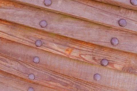 Pattern slanted boards dark brown with a row of rivets iron and rust Stock Photos
